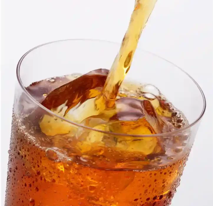 Photographie d'un Thé Frappé. La liqueur du thé noir est versée dans un long verre où des glaçons sont rajoutés. Le fond est blanc