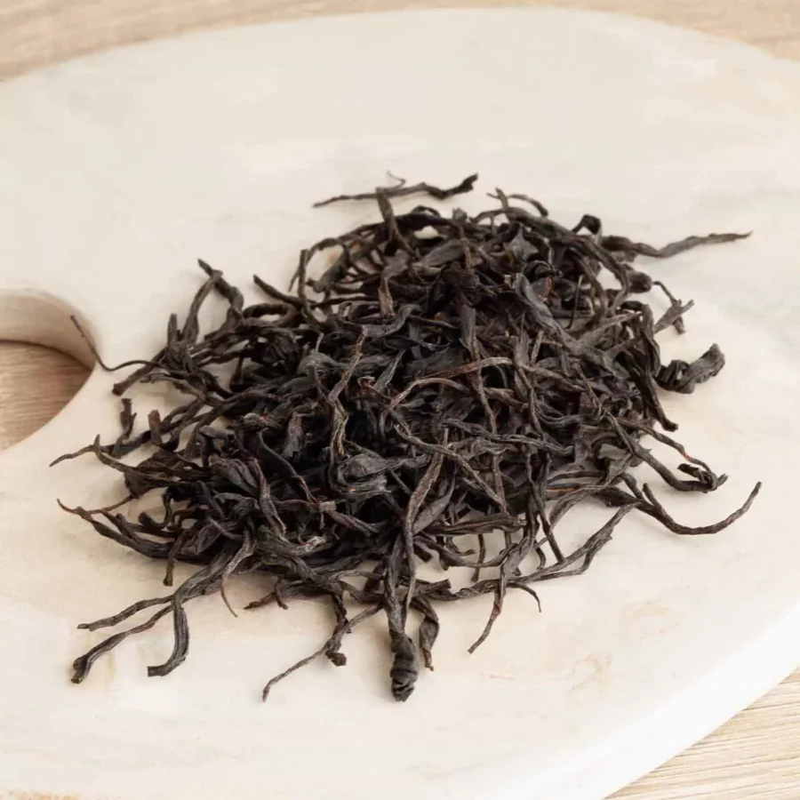Feuilles d'un thé noir récolté à la main. Sur un support en céramique avec une effet marbre. Le fond est du bois. Un coffret sur mesure pour vos collaborateurs