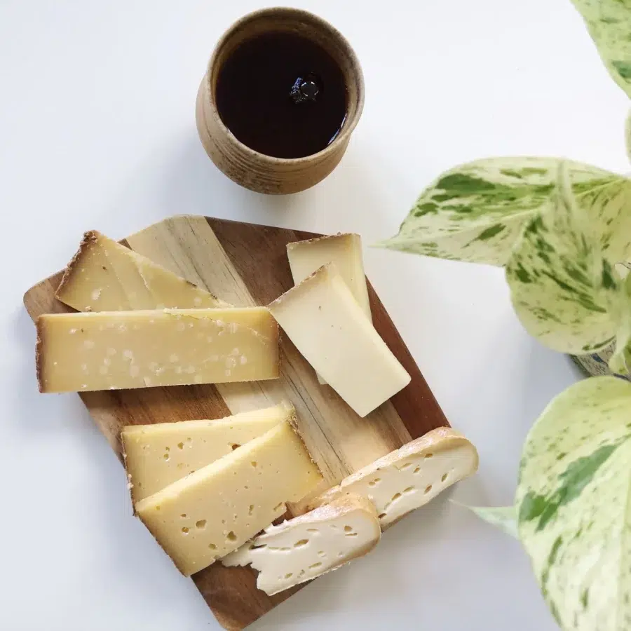 Une tasse de thé chaude, en dessous sur une planche en bois plusieurs fromages Formation thé professionnels