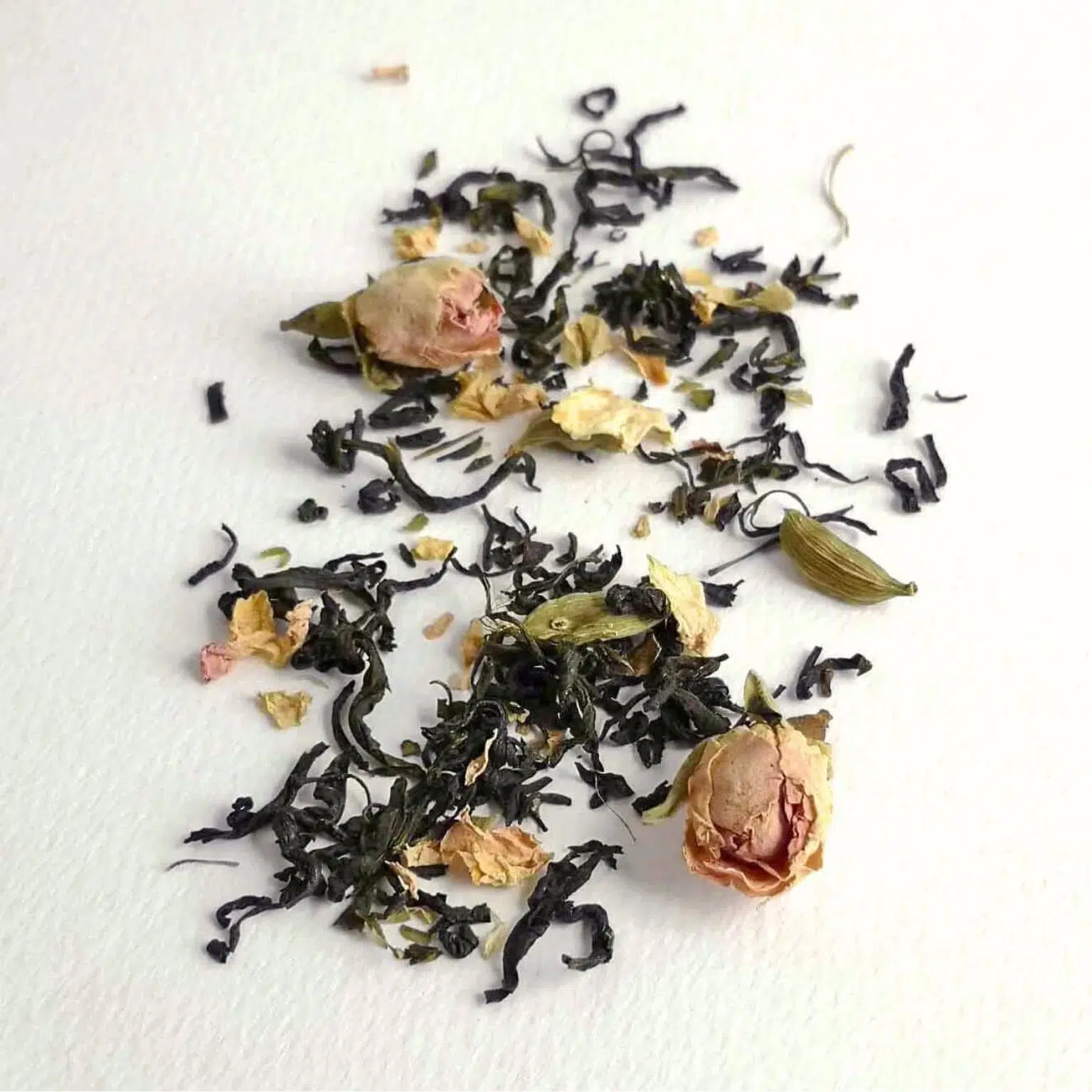 Photographie packshot du thé vert Éclosion Divine présentant les feuilles de thé avec des bourgeons et pétales de roses et des Cardamomes