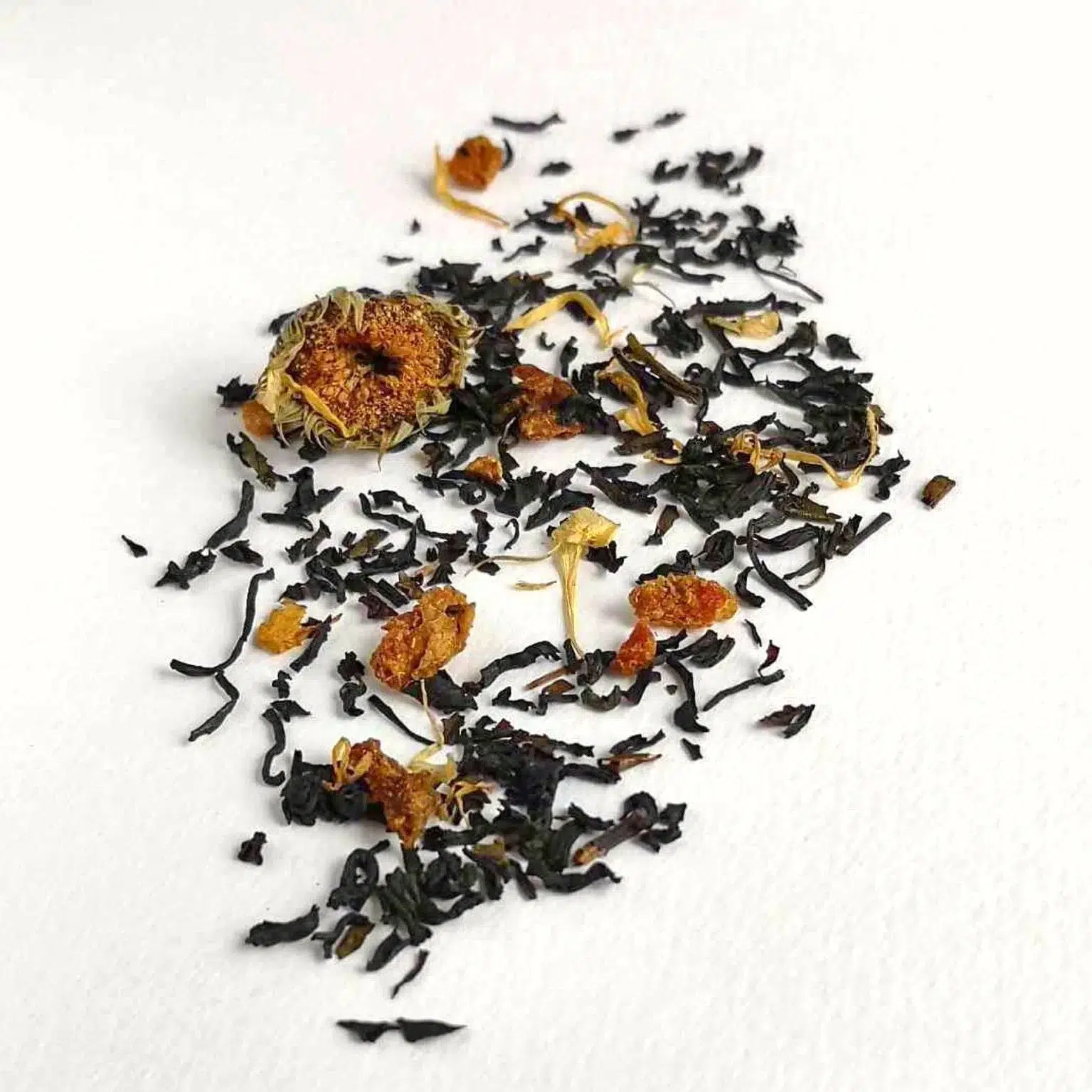 Photographie Packshot du thé Étincelle D'Hiver, un mélange de thé oolong fortement oxydé, noir et hojicha avec des fleurs de soucis, poire, chataîgne, écorces d'oranges.